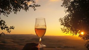 Bicchiere di birra al tramonto con il panorama che si vede da Montenero d'Orcia
