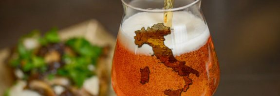 Bicchiere decorato con forma dell'Italia e collo di bottiglia che versa birra artigianale