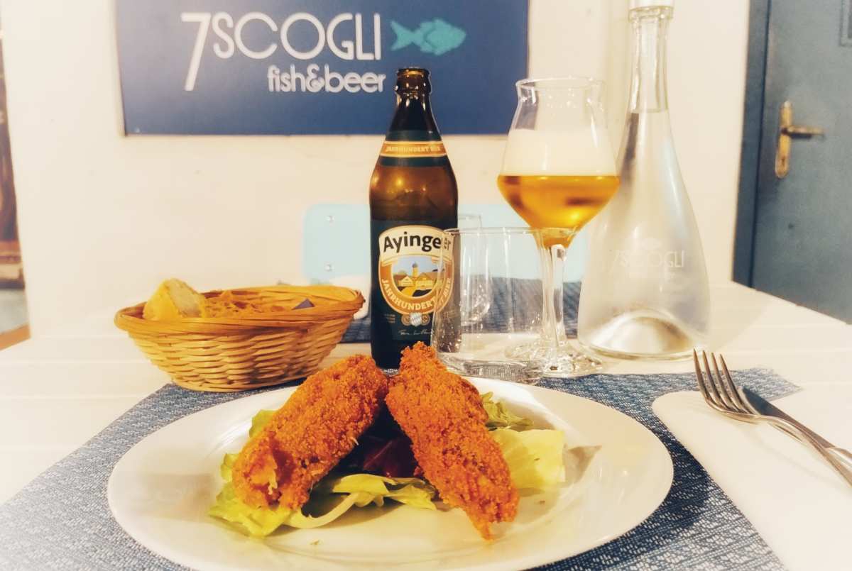 Piatto di pesce, birra tedesca e logo del ritorante 7 scogli di Firenze