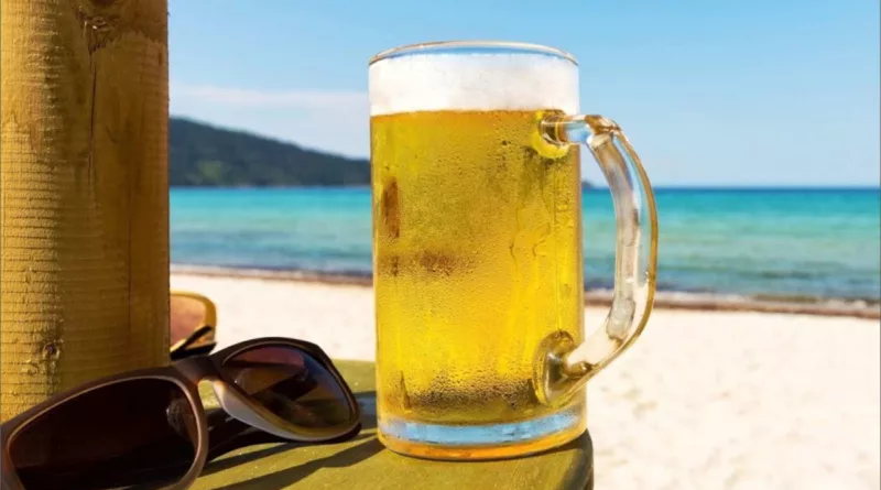 Birra d'estate con spiaggia in sottofondo